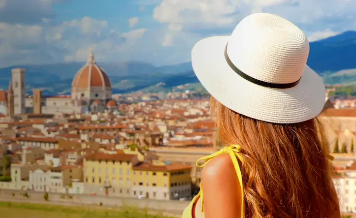 Woman in a white hat admiring the panoramic view of Florence, including the iconic Duomo.