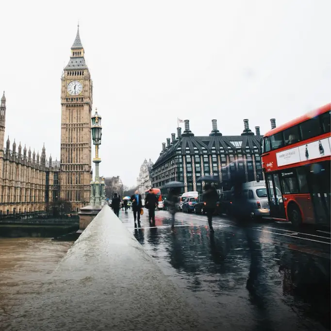 Rainy day in London with Big Ben and a red double-decker bus on Westminster Bridge.