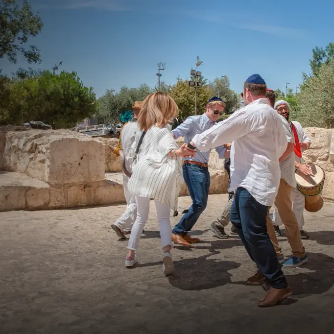 Group of people holding hands and dancing in a Bar Mitzvah celebration in a circle