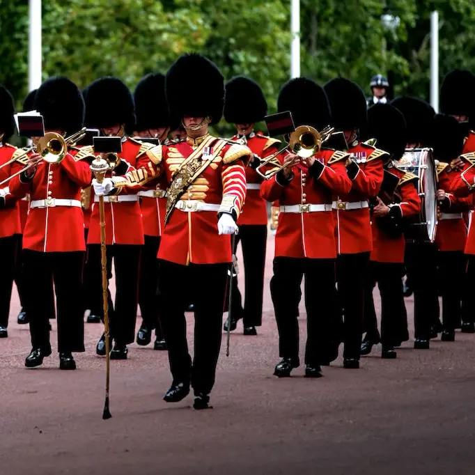 Marching band of the British Royal Guards in red uniforms and black bearskin hats.