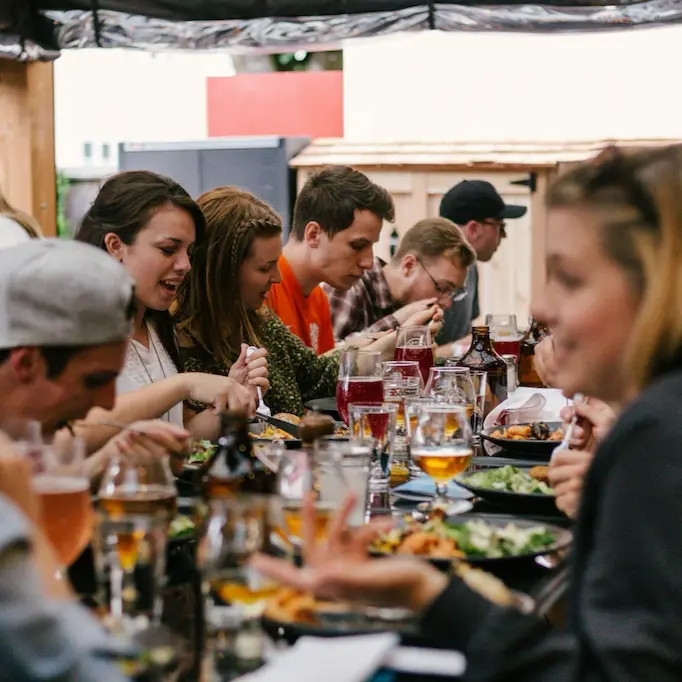 Group of people enjoying a meal together at a long outdoor table in a restaurant in England