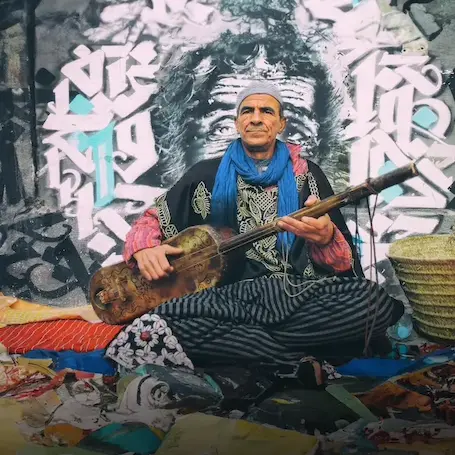 Street Jordanian musician playing a traditional instrument against a backdrop of colorful graffiti.