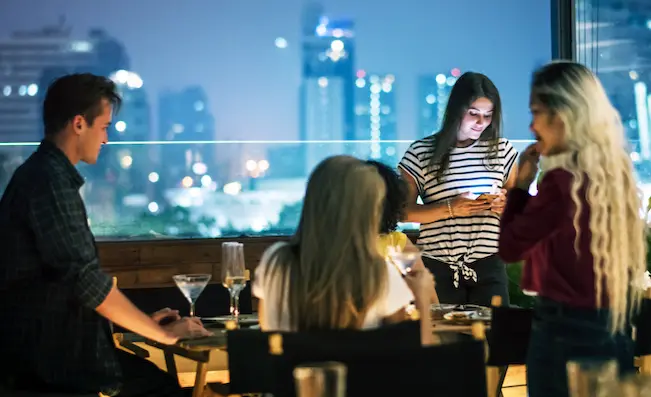 A group enjoying cocktails with a panoramic view of Madrid’s skyline at an exclusive rooftop bar, featured in Shin-Tours luxury night tours